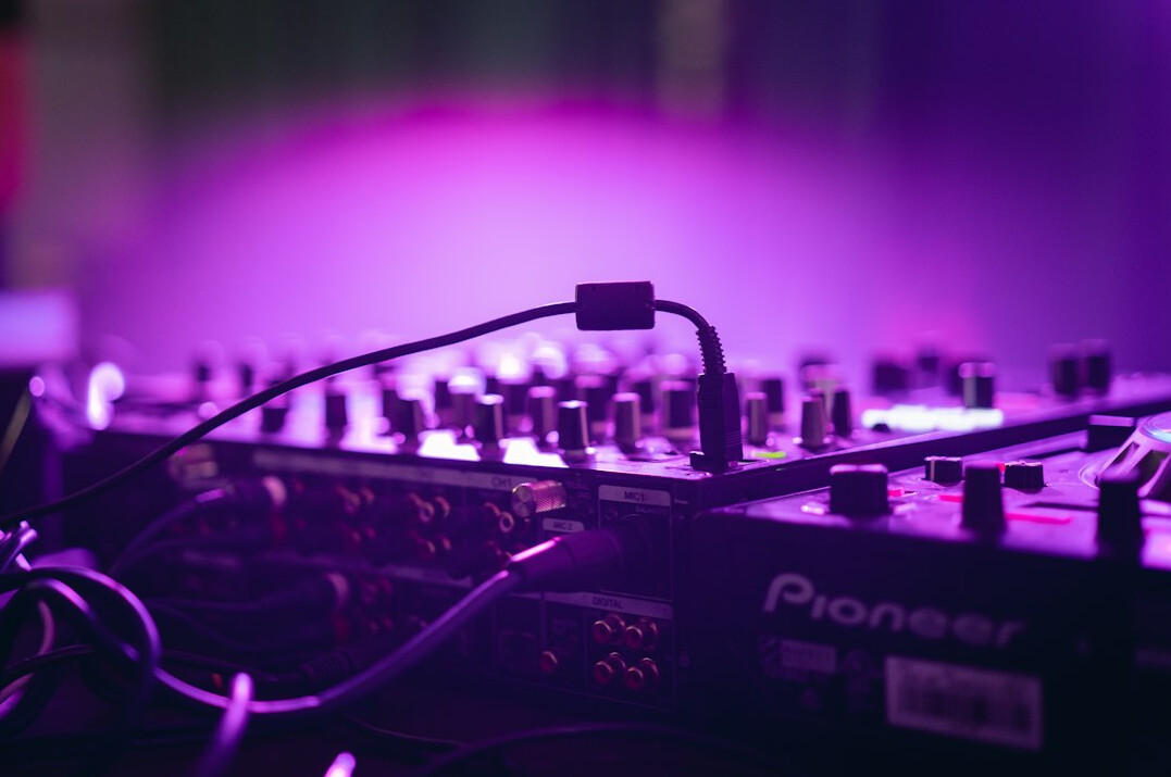Close-up of a professional audio mixing console with sliders and VU meters